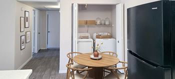 A small table with four chairs in a kitchen with a refrigerator and washer and dryer